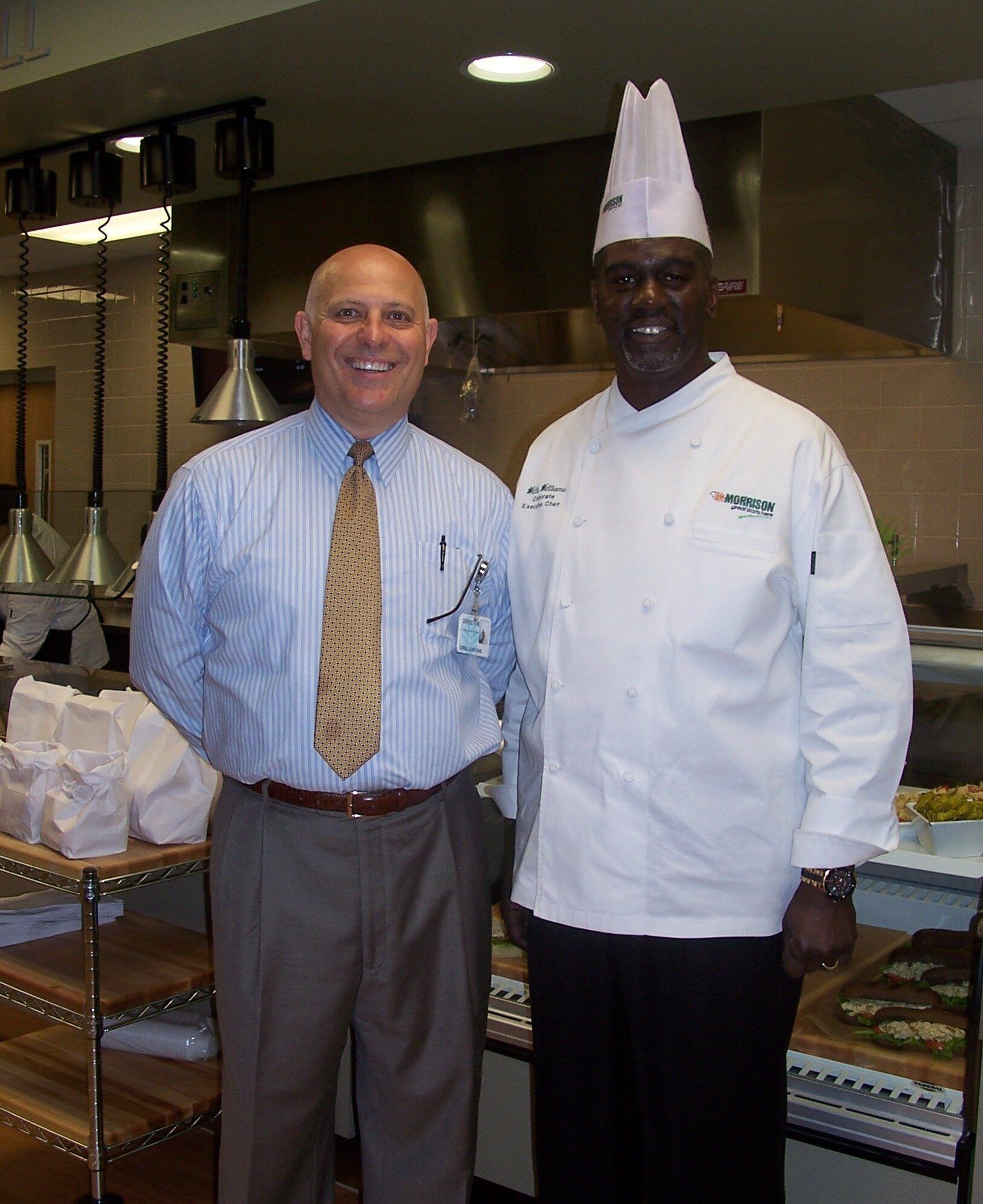 Greg Gorgone stands with a Morrison Healthcare executive chef in a commercial kitchen.