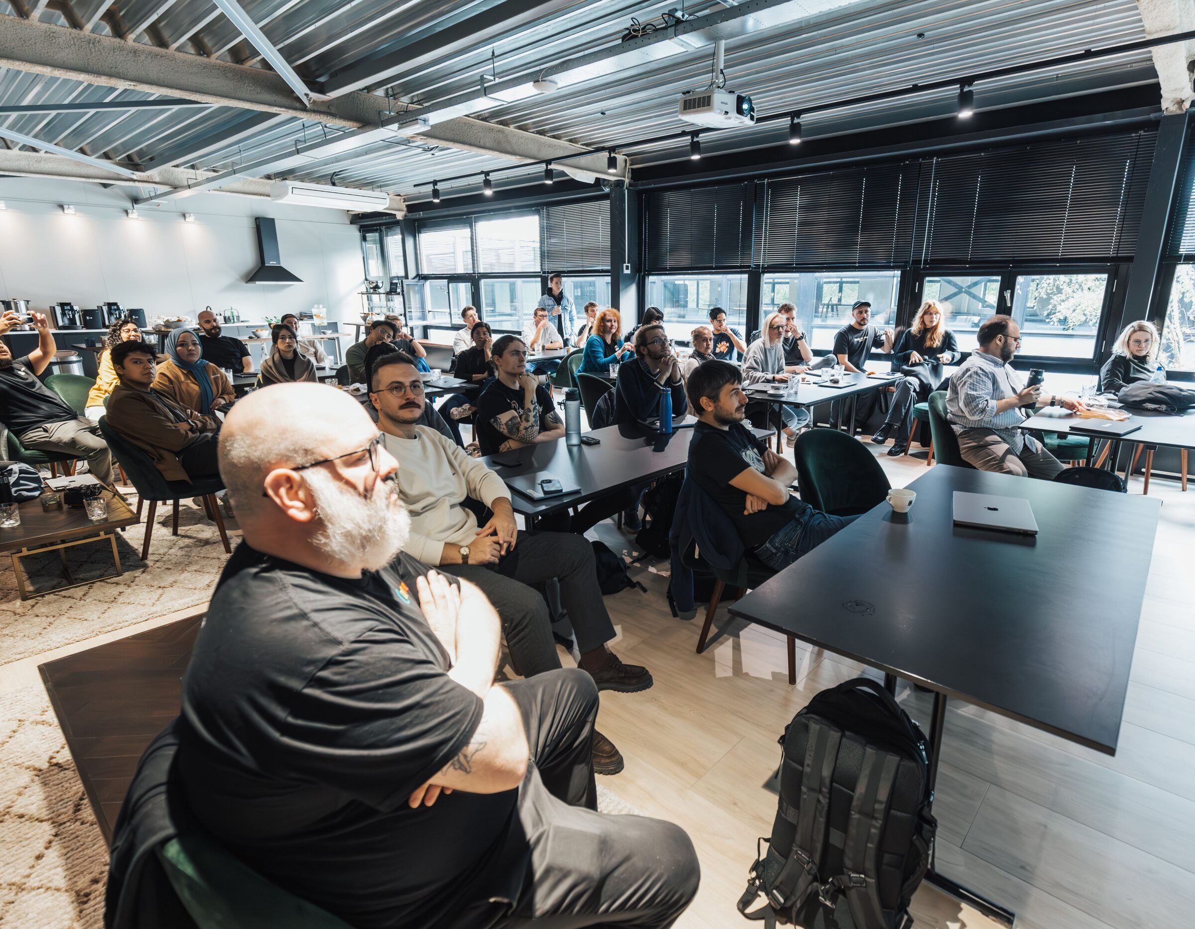 A packed seminar room listens attentively as a speaker presents to the group.